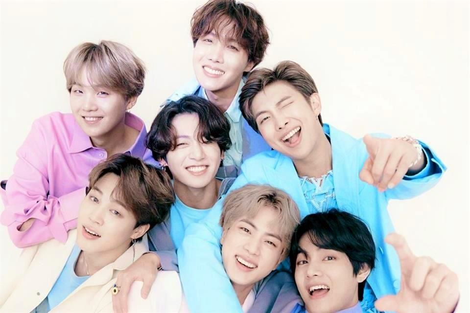BTS en alfombra roja con trajes elegantes frente a fondo de premios