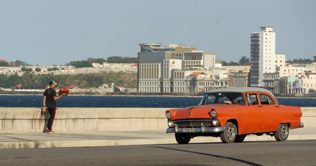 Automóvil clásico circula por el malecón de La Habana con poca presencia de turistas.