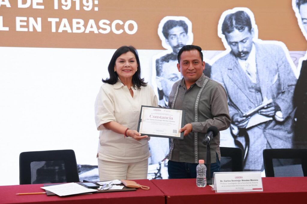La alcaldesa Yolanda Osuna Huerta entrega una constancia a un investigador durante el panel histórico sobre la Constitución de 1917 y 1919 en Villahermosa.