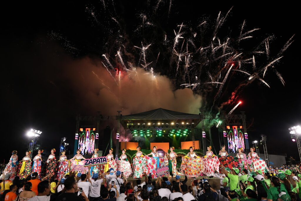 Las 17 embajadoras juntas, al fondo los fuegos artificiales.