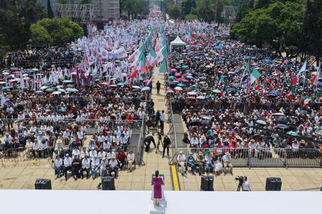 Vista cenital desde el escenario del mitin en el Monumento a la Revolución, mostrando a la presidenta Sheinbaum ante una multitud que se extiende por toda la avenida el 1 de junio de 2025